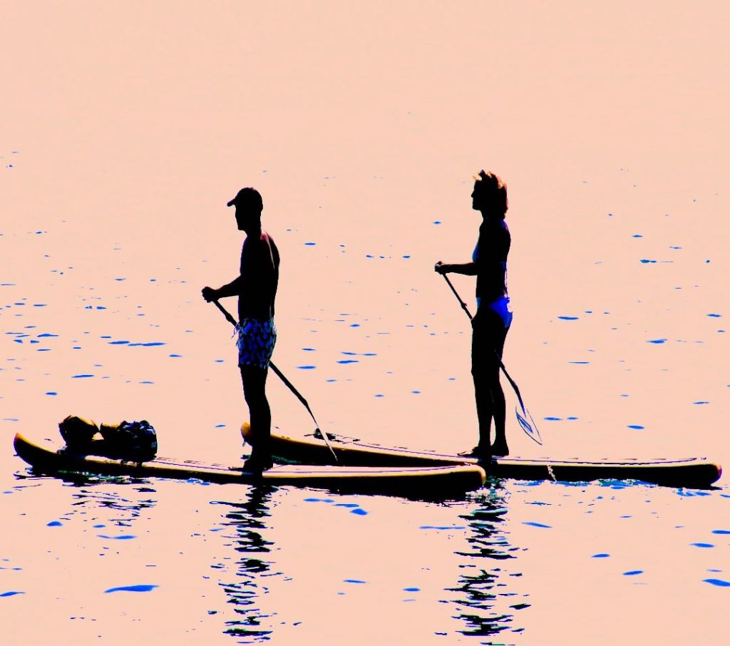 Couple on 2 SUP Boards Stand Up Paddling together