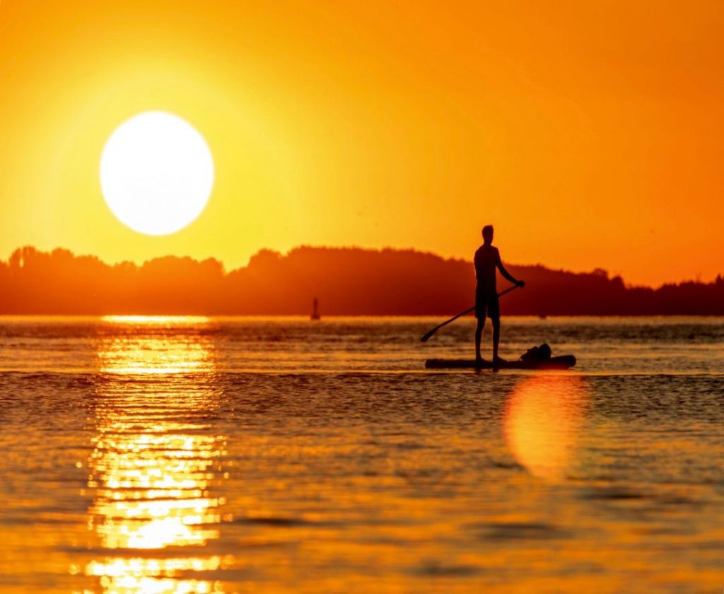 Herrlicher Sonnenuntergang und Stand Up Paddler auf SUP Board