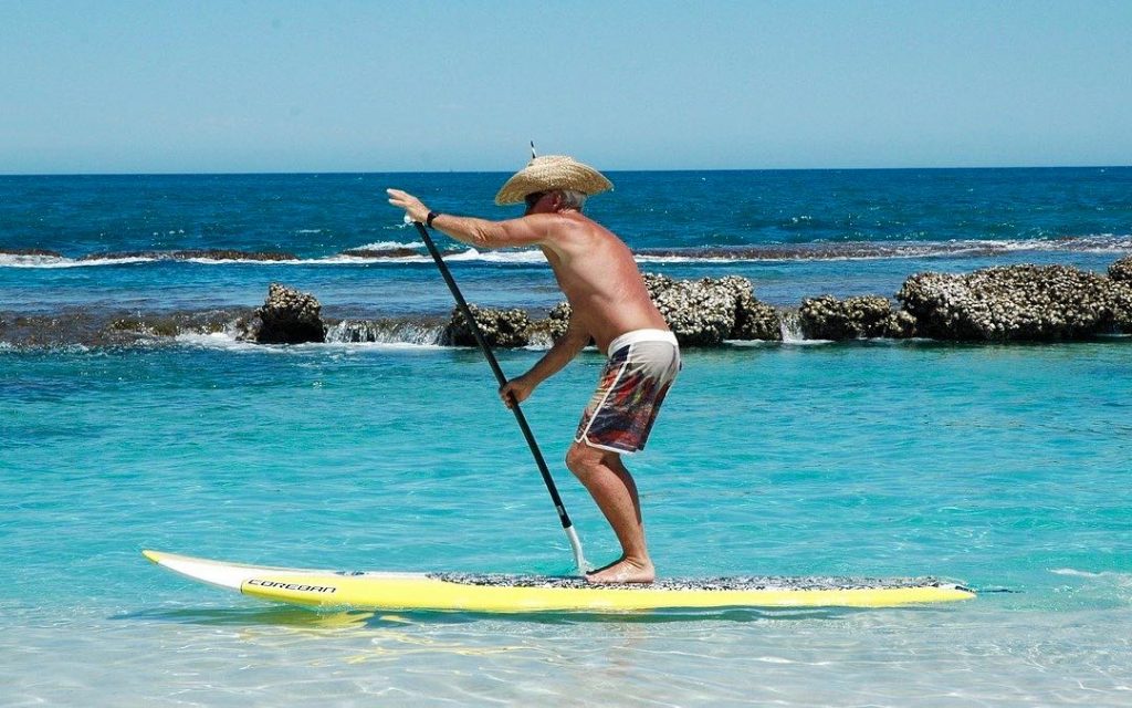 Coll man with cowboy hat on SUP Board. Stand Up Paddling